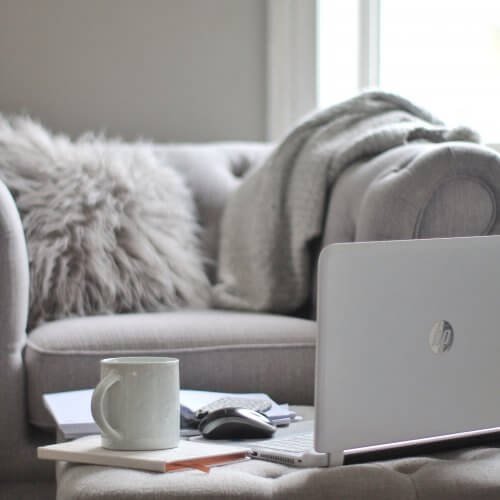 Grey sofa with laptop and cup by Wildflower Pinterest Management in the UK