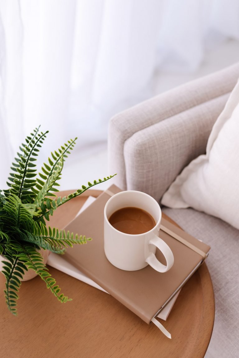 Desk top scene with fern, coffee cup and notebook - Wildflower Pinterest Management